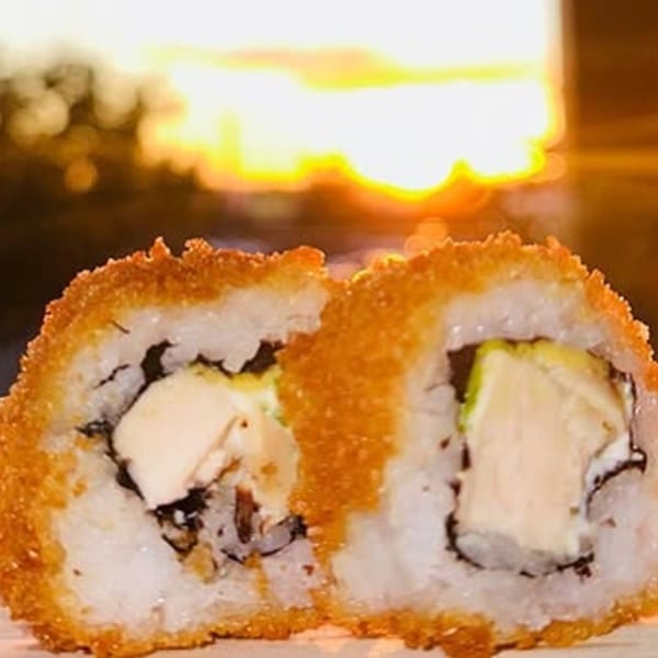 Two pieces of crispy fried sushi with white rice, cream cheese, and avocado filling.