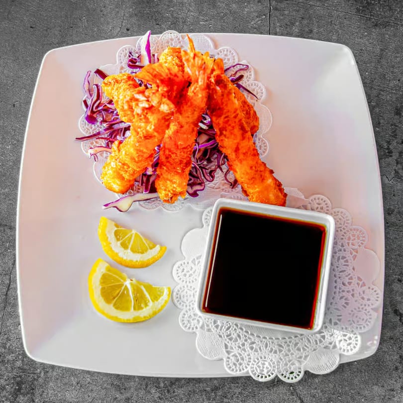 Crispy fried shrimp tempura with shredded red cabbage, lemon wedges, and a side of soy sauce.
